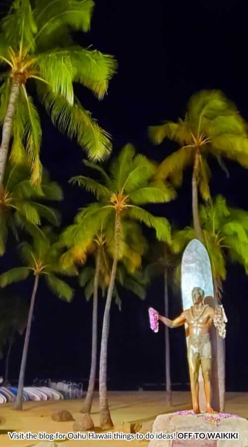 duke kahanamoku statue at night waikiki beach